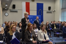 uczestnicy konferencji siedzą na auli, jeden uczestnik mówi przez mikrofon