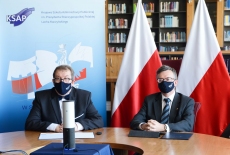 Dyrektor KSAP i Szef Służby Cywilnej podczas konferencji - w bibliotece, na tle polskich flag i baneru KSAP